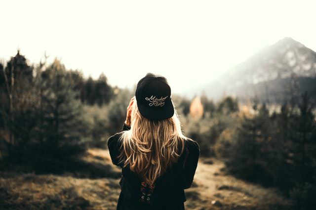 woman with backwards cap looking at mountain landscape