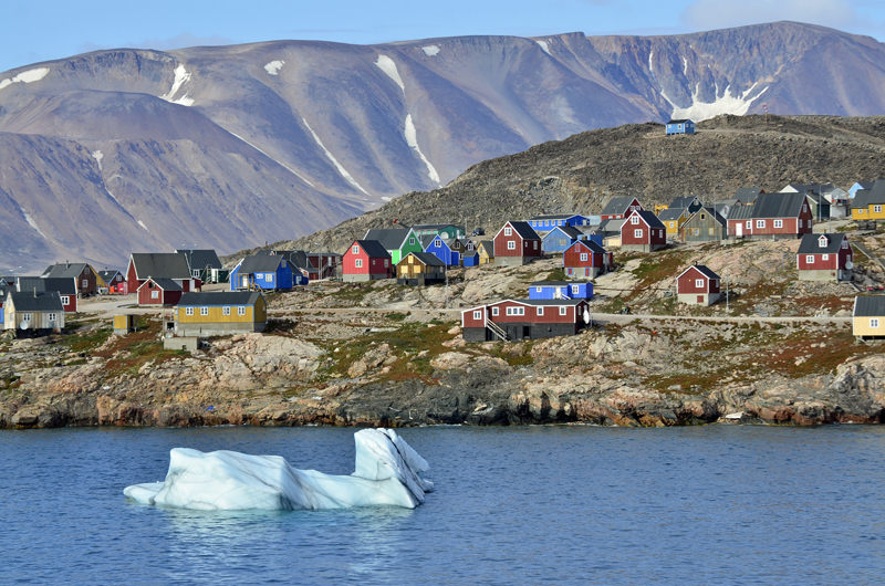 Iceberg and houses on Ittoqqortoormiit, Greenland.
