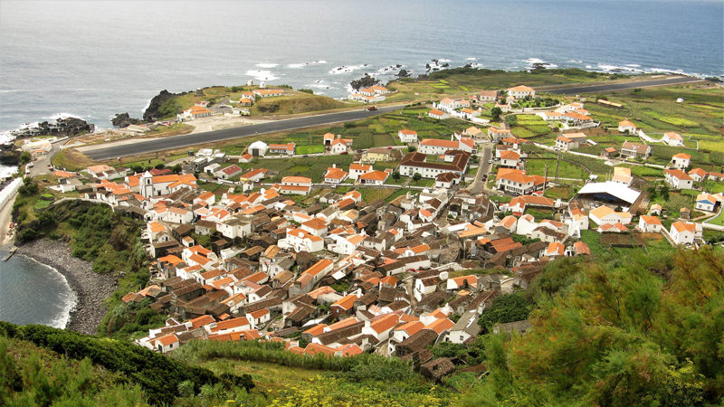 Casas y pista de aterrizaje en Crovo, Azores, con el océano al fondo.