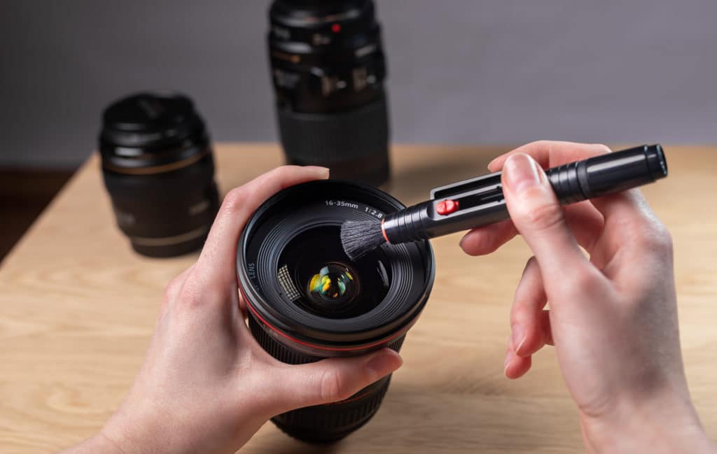 Canon full-frame DSLR camera lens being cleaned with lens pen.