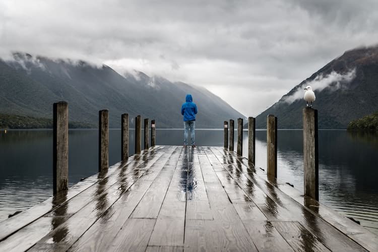 gloomy and rainy day with man standing on a dock in front of lake