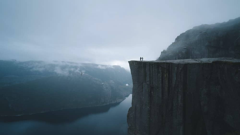 2 hikers in Preikestolen, Norway, with moody scenery