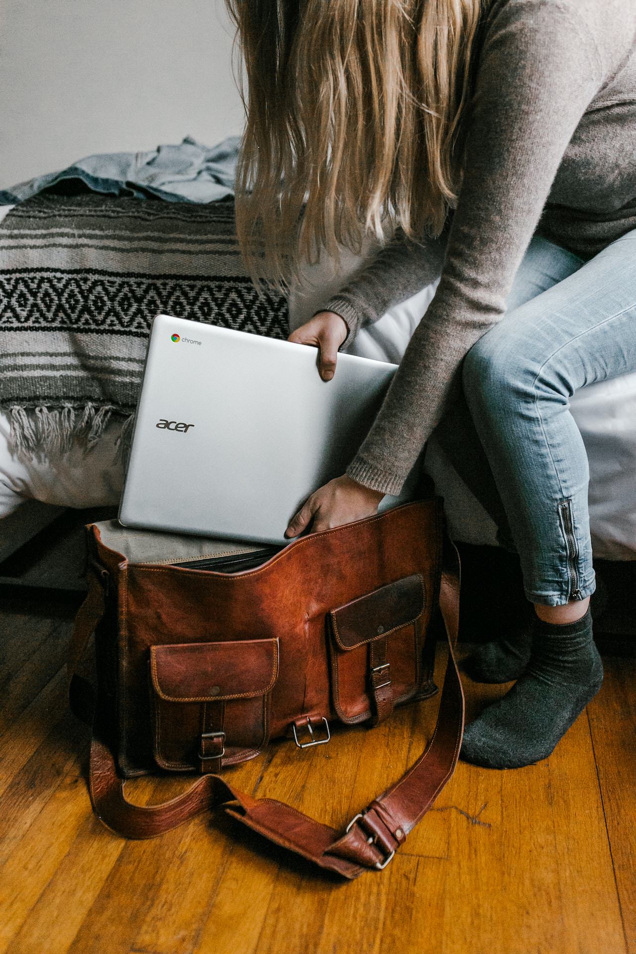 ¿Cuentan los bolsos para portátiles como equipaje de mano? Mujer colocando un portátil en una bolsa de mensajero.