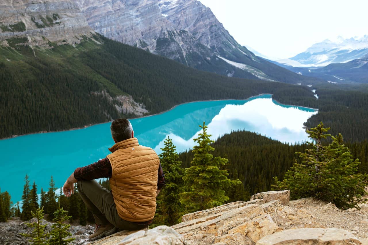 Landscape photo of Peyto Lake in Canada with man sitting in foreground.